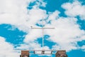 A white wooden cross against a blue sky with clouds, a seagull sits on the edge Royalty Free Stock Photo