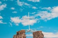 A white wooden cross against a blue sky with clouds, a seagull sits on the edge Royalty Free Stock Photo