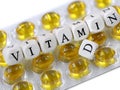 white wooden cubes with black letters form the text Vitamin D on yellow pill blister
