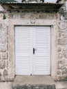 White wooden door with a black handle in a stone fence near an old house Royalty Free Stock Photo