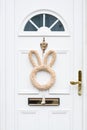 White wooden door with Easter bunny wreath. Minimalist Easter decoration Royalty Free Stock Photo