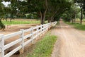 White wooden fence around the ranch and country road with tree Royalty Free Stock Photo