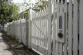 White wooden fence in a sunny street with a letterbox and newspaper hole Royalty Free Stock Photo