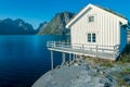 White, wooden fisherman`s house with grass on the roof in Reine, Lofoten, Norway. Sunset of a sunny day in the village by the sea Royalty Free Stock Photo