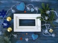 White wooden frame decorated with fir branches, Christmas-tree lighting with snowflakes, felt hearts on a blue wooden textural bac Royalty Free Stock Photo