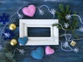 White wooden frame decorated with fir branches, Christmas-tree lighting with snowflakes, felt hearts on a blue wooden textural bac Royalty Free Stock Photo