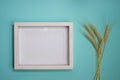 A white wooden frame with a wheat on a mint background.