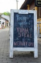 White wooden framed chalkboard, handwritten today`s special menu, display on outdoor street pavement Royalty Free Stock Photo