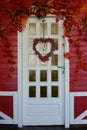 White wooden front door decorated in autumn, with red leaves, berries and a wreath Royalty Free Stock Photo