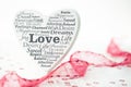 White wooden heart with different english words concerning love and red ribbon and heart confetti on white grey wooden underground Royalty Free Stock Photo