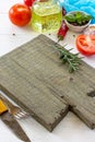 White wooden kitchen background. Cutting board and fresh vegetables, olive oil and spices on the kitchen table Royalty Free Stock Photo