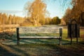 White wooden park bench with metallic parts pictured from the backside. Black metallic trash can or trash bin next to it. Royalty Free Stock Photo