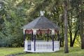 White wooden pavilion or gazebo in a beautiful summer garden. Trees and green grass in background Royalty Free Stock Photo