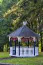 White wooden pavilion or gazebo in a beautiful summer garden. Trees and green grass in background Royalty Free Stock Photo