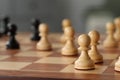 White wooden pawns on chess board, selective focus. Space for text