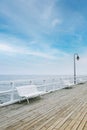 White wooden pier, blue sky, sea. White benches on the pier. Royalty Free Stock Photo