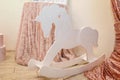 White wooden rocking horse on pink shiny fabric background. Little girl room interior or first birthday Royalty Free Stock Photo