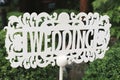 White wooden sign in the form of an arrow and a pointer with the inscription and letters - wedding in English stands in