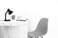 White wooden table with black lamp, notebook, mug and moneybox