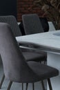 White wooden table combined with gray wooden chairs with soft fabric upholstery. There is a black glass vase with dried Royalty Free Stock Photo