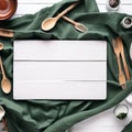 White wooden table covered with green tablecloth and cooking utensils. View from top. Empty tablecloth for product montage Royalty Free Stock Photo