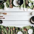 White wooden table covered with green tablecloth and cooking utensils. View from top Royalty Free Stock Photo