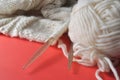 White wool knitting needles and handmade knits on bright orange background