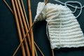 white wool knitting needles and a piece of knitting against a black background Royalty Free Stock Photo