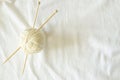 White wool thread ball with wooden bamboo knitting needles on white linen fabric background. Top view, copy space. Hobby Royalty Free Stock Photo