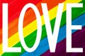 White word LOVE isolated on rainbow colors background close up, LGBT community flag banner, LGBTQ pride poster, letter love sign