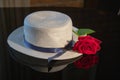 White woven straw hat with a blue ribbon and a red rose on a black background Royalty Free Stock Photo