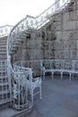 A white, wrought-iron semicircular bench and a fragment of a luxurious openwork staircase leading to the gallery of the Catherine