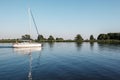 A white yacht with lowered sails sails in the lagoon. Quiet evening, well visible reflection of the ship`s mast in the water.