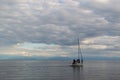 white yacht with people floats in silver clear lake baikal, in the morning, background of blue mountains on the horizon