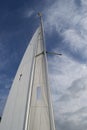 White yacht sail and metal mast against bright blue sky with clouds Royalty Free Stock Photo