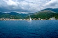 White yacht with a sail in the sea against the backdrop of the coastline of the mountains Royalty Free Stock Photo