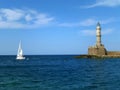 White Yacht Sailing near the Historic Lighthouse at Old Venetian Harbor in Chania, Crete Island of Greece Royalty Free Stock Photo