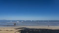 White yachts are visible in the blue ocean. A wooden fishing boat with a mast is moored in shallow water. The waves roll towards t Royalty Free Stock Photo