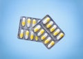 White yellow capsule pills in blister pack on blue background Royalty Free Stock Photo