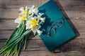 White and yellow daffodils, book and glasses on a wooden background