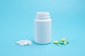 White, yellow and green pills, tablets and white bottle on blue background Royalty Free Stock Photo