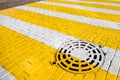 White and yellow pedestrian crossing with storm sewer hatch