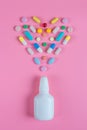 White, yellow, red, blue pills, tablets and white bottle on pink background Royalty Free Stock Photo