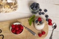 White yogurt glass jar with fresh raspberries and blueberries on serving board on rustic table, wooden tray as background, copy Royalty Free Stock Photo