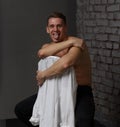 White young guy sitting on a chair near a gray brick wall, black-and-white photo Royalty Free Stock Photo