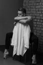 white young guy sitting on a chair near a gray brick wall, black-and-white photo Royalty Free Stock Photo