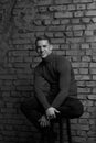 white young guy sitting on a chair near a gray brick wall, black-and-white photo Royalty Free Stock Photo