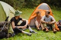 Young travelers resting in tents while hiking in green forest