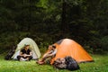 Young travelers resting in tents while hiking in green forest