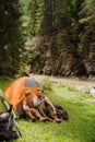 Young travelers resting in tents while hiking in green forest